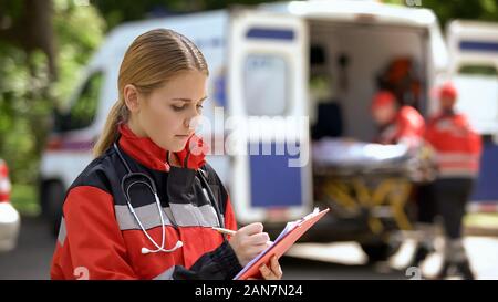 Femme médecin garder les dossiers médicaux, les ambulanciers transport de patient Banque D'Images