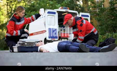 Le personnel du service d'ambulance de soins patient sur route, mettre l'équipement intraveineuse Banque D'Images