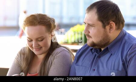 Fat timide couple sitting in outdoor cafe au cours date romantique, situation délicate Banque D'Images