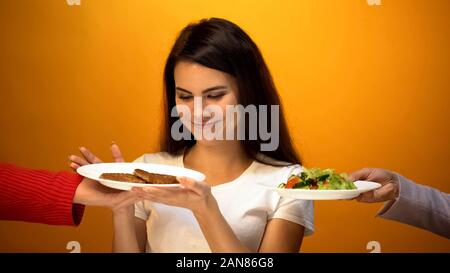 Girl choosing viande au lieu de la salade, rejet du véganisme, la nutrition saine Banque D'Images