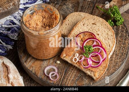 Tranches de pain slathered avec porc saindoux mélangé avec sol crépitements avec des rondelles d'oignon sur le dessus sur un fond rustique Banque D'Images