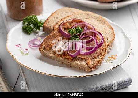 Tranches de pain slathered avec porc saindoux mélangé avec sol crépitements, avec des rondelles d'oignon sur le dessus Banque D'Images