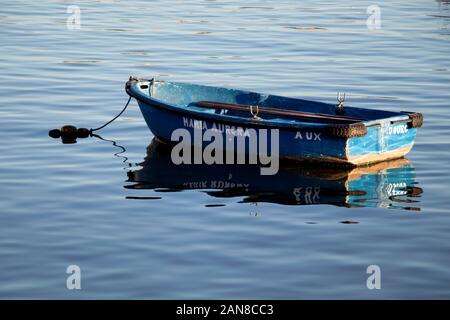 Bateau à rames en bois bleu flottant sur l'eau calme avec reflets Banque D'Images