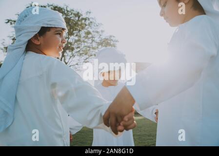 Les enfants jouer ensemble à Dubaï dans le parc. Groupe d'enfants portant des kandura traditionnelle robe blanche de arabes unis Banque D'Images