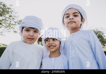 Les enfants jouer ensemble à Dubaï dans le parc. Groupe d'enfants portant des kandura traditionnelle robe blanche de arabes unis Banque D'Images