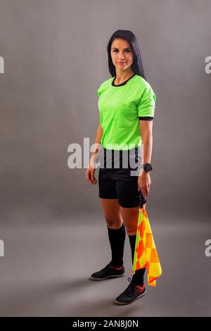 Belle arbitre de football avec le drapeau dans la main à la caméra et au sourire Banque D'Images