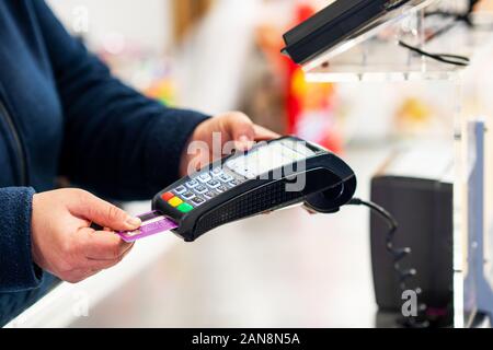 Balayez avec la carte bancaire à la main terminal de point de paiement dans un magasin. Banque D'Images