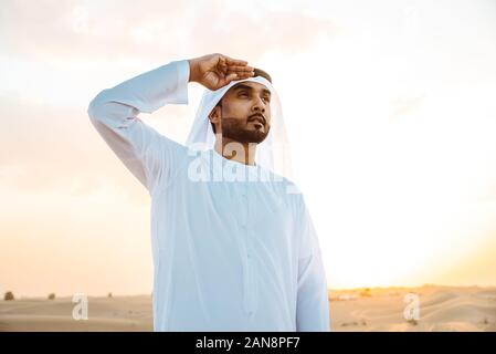 Les hommes d'affaires des eau traditionnelles kandura blanche passer du temps dans le désert de Dubaï Banque D'Images