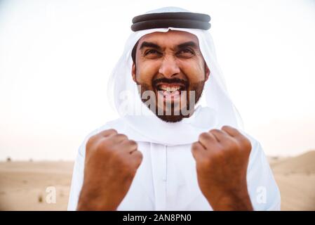 Les hommes d'affaires des eau traditionnelles kandura blanche passer du temps dans le désert de Dubaï. Banque D'Images