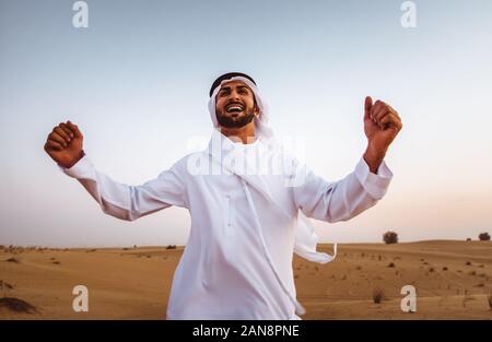 Les hommes d'affaires des eau traditionnelles kandura blanche passer du temps dans le désert de Dubaï. Banque D'Images