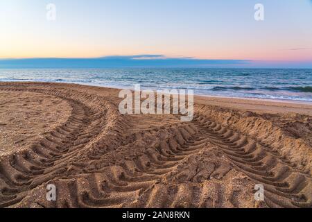 Les marques de la bande de roulement des pneus sur le sable par la mer Banque D'Images