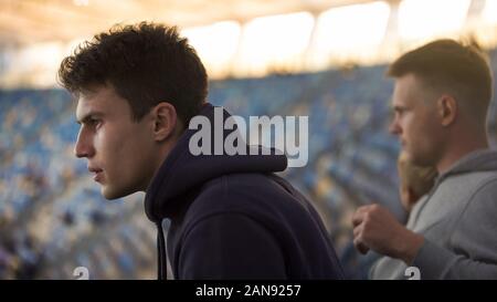 Regarder attentivement des fans masculins jeu sport à stade, temps libre avec des amis Banque D'Images