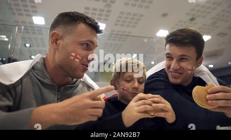 Les amateurs de football anglais mangeant des hamburgers après le match, effet nocif de la restauration rapide Banque D'Images