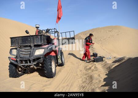 (200116) -- XAYAR , 16 janvier 2020 (Xinhua) -- Zhou Fuxiang change la batterie dans le désert Taklimakan, nord-ouest de la Chine, la Région autonome du Xinjiang Uygur, 15 janvier 2020. L'exploration d'huile de BGP travailleurs Inc., China National Petroleum Corporation, dont plus de 60 sont des femmes, sont engagés dans un travail acharné dans le désert Taklimakan. (Xinhua/Ding Lei) Banque D'Images