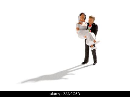 Scène juste marié avec un balai en tenant son épouse sur ses mains. Petites gens monde miniature isolé sur fond blanc avec ombre Banque D'Images