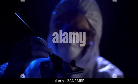 Criminaliste collecter les empreintes digitales de téléphone cellulaire, preuve de scène de crime Banque D'Images