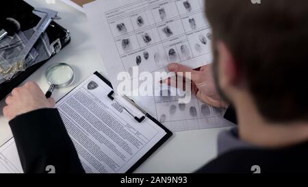 Les empreintes digitales de l'examen de détective d'informations, à l'aide d'une loupe, d'identité Banque D'Images