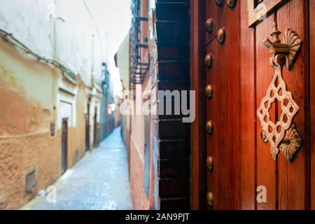Heurtoir en métal sur la porte en bois dans la rue étroite de la vieille ville de Marrakech, Maroc Banque D'Images
