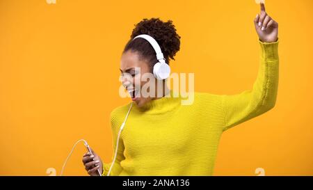 Femme insouciante sur fond lumineux chant millénaire portant des écouteurs, fun Banque D'Images