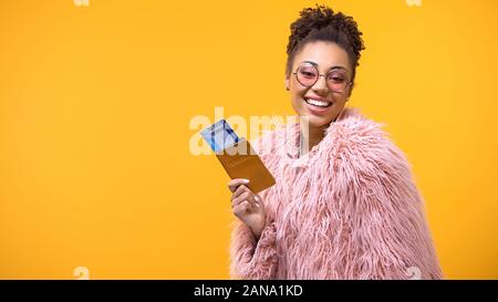 Smiling african woman showing passeport et billets de voyage sur fond jaune Banque D'Images