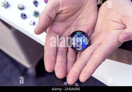 Bille de verre avec l'image de l'univers, des étoiles et des planètes dans les mains de l'homme. Le concept d'un monde fragile. Banque D'Images