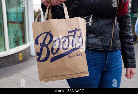 Jeune femme portant un papier Boots the Chemist panier UK Banque D'Images