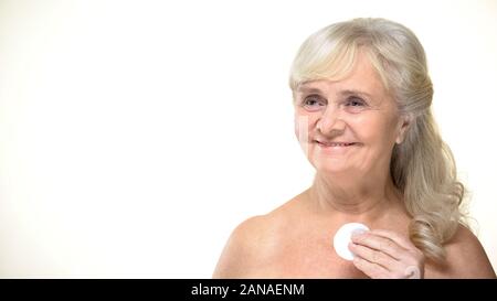 Vieille femme joyeuse à l'aide de clavier pour le nettoyage de la peau, soins de beauté, Cosmétiques Banque D'Images