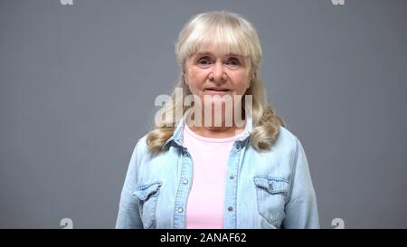 Portrait d'une femme âgée dans les tenues de isolé sur l'âge de la retraite, gris Banque D'Images