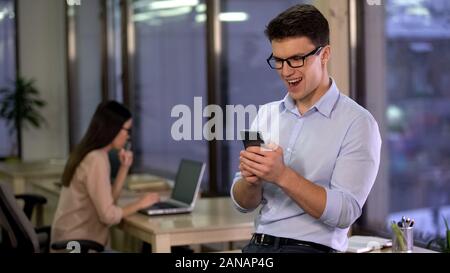 L'homme excité à l'aide d'application smartphone dans office, la technologie moderne, gadget Banque D'Images