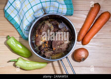 Traditionnellement les steaks en sauce avec carottes et oignons offert comme libre dans une casserole en fonte sur une table en bois Banque D'Images