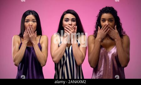 Choqué pour la fermeture de la bouche avec les mains contre fond rose, potins news Banque D'Images