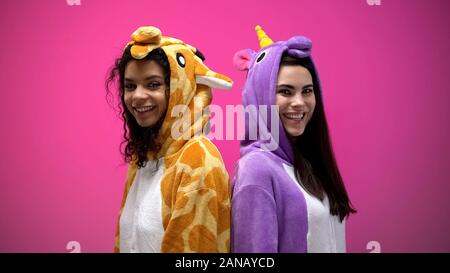 L'Interracial amis de licorne et de costumes girafe debout dos à dos, sourire Banque D'Images