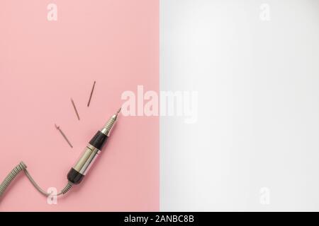 Ongle manucure électrique forage machine avec différents outils de forage sur fond géométrique rose et blanc Banque D'Images