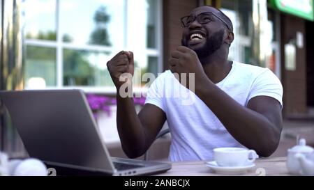 Bonne lecture homme-news e-mail sur l'ordinateur portable dans un café, gagnant de loterie Banque D'Images