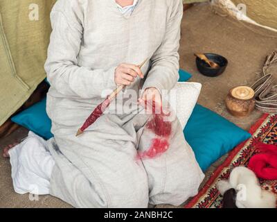 Femme en robe de coton médiévale spinning avec une roue. Fils d'une dame fait de la laine des moutons. Les fusées de la main. La roue tournante. Filer. Traiter Banque D'Images