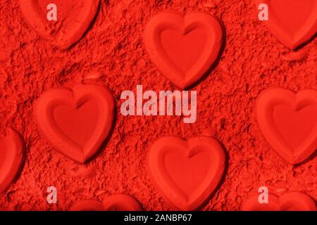 Arrière-plan de la Saint-Valentin faite de cœur gravé sur poudre rouge. Banque D'Images
