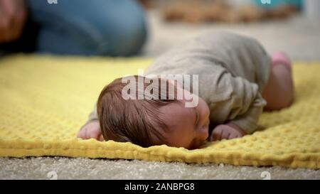 Adorable petite fille bébé couché sur le ventre en essayant de ramper, le développement du nouveau-né Banque D'Images