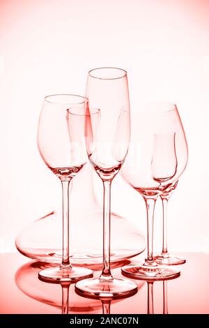 Verrerie sélection avec le vin, champagne, liqueur verres et la carafe sur l'arrière-plan clair.. Verrerie cristal Fine concept. La verticale. Corail vivant - Thème couleur de l'année 2019 Banque D'Images