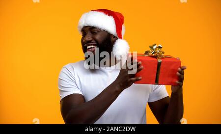 L'homme afro in Santa hat holding Christmas Gift, et des fêtes Banque D'Images