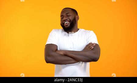 L'homme afro-américain confiant rire avec mains croisées, histoire drôle Banque D'Images