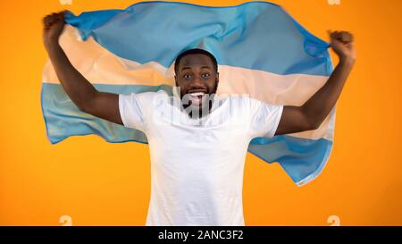 Black man holding drapeau argentin, célébrant la victoire de l'équipe de sports de favori, ventilateur Banque D'Images
