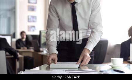Gestionnaire de contrat de lecture mâle, préparent des documents en vue de l'ordre du jour de la réunion de planification, Banque D'Images