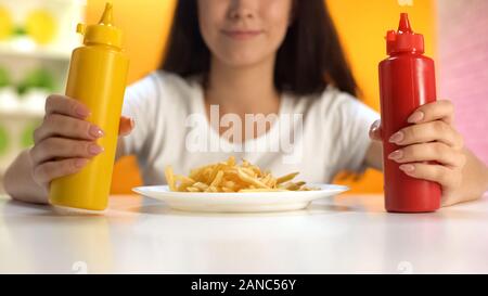 Brunette woman holding Ketchup et Moutarde sur plaque frites, repas malsains Banque D'Images