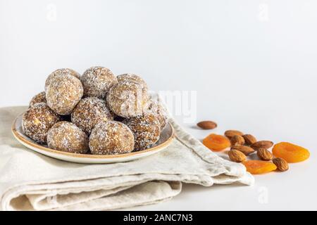 Boulettes d'énergie maison avec abricots secs, raisins secs, dattes, pruneaux, noix de Grenoble, amandes et noix de coco. Des aliments sucrés sains. Boules d'énergie dans une plaque Banque D'Images