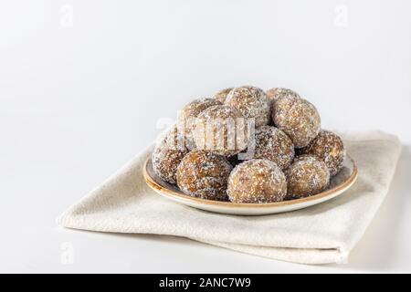 Boulettes d'énergie maison avec abricots secs, raisins secs, dattes, pruneaux, noix de Grenoble, amandes et noix de coco. Des aliments sucrés sains. Boules d'énergie dans une plaque Banque D'Images