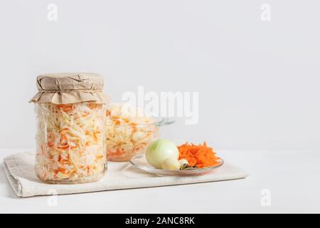 Choucroute faite maison avec des carottes dans un bocal en verre et bol sur un fond de bois blanc. Les aliments fermentés. Copier l'espace. Banque D'Images