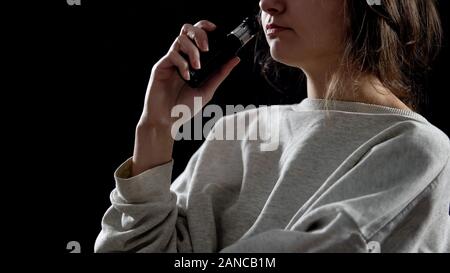 Jeune femme avec la cigarette électronique, appareil pour fumeurs, vapeur de simulation Banque D'Images