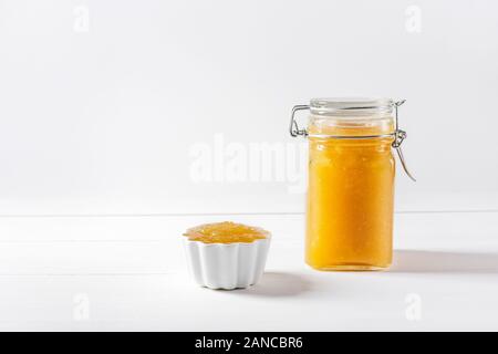 Confiture de fruits délicieux faits maison dans un bocal en verre et bol sur fond blanc. Copier l'espace. Vue de côté. Banque D'Images