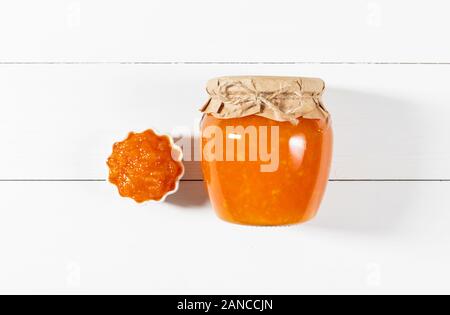 Une délicieuse confiture faite maison dans un bocal en verre sur un fond de bois blanc. Haut de la vue, télévision lay. Banque D'Images