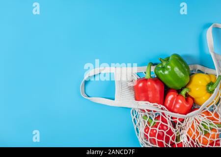 Concept zéro déchet. Légumes à l'éco-sac chaîne réutilisables sur fond bleu. Articles de plastique. La nourriture végétarienne frais et sain. Mise à plat, vue du dessus Banque D'Images